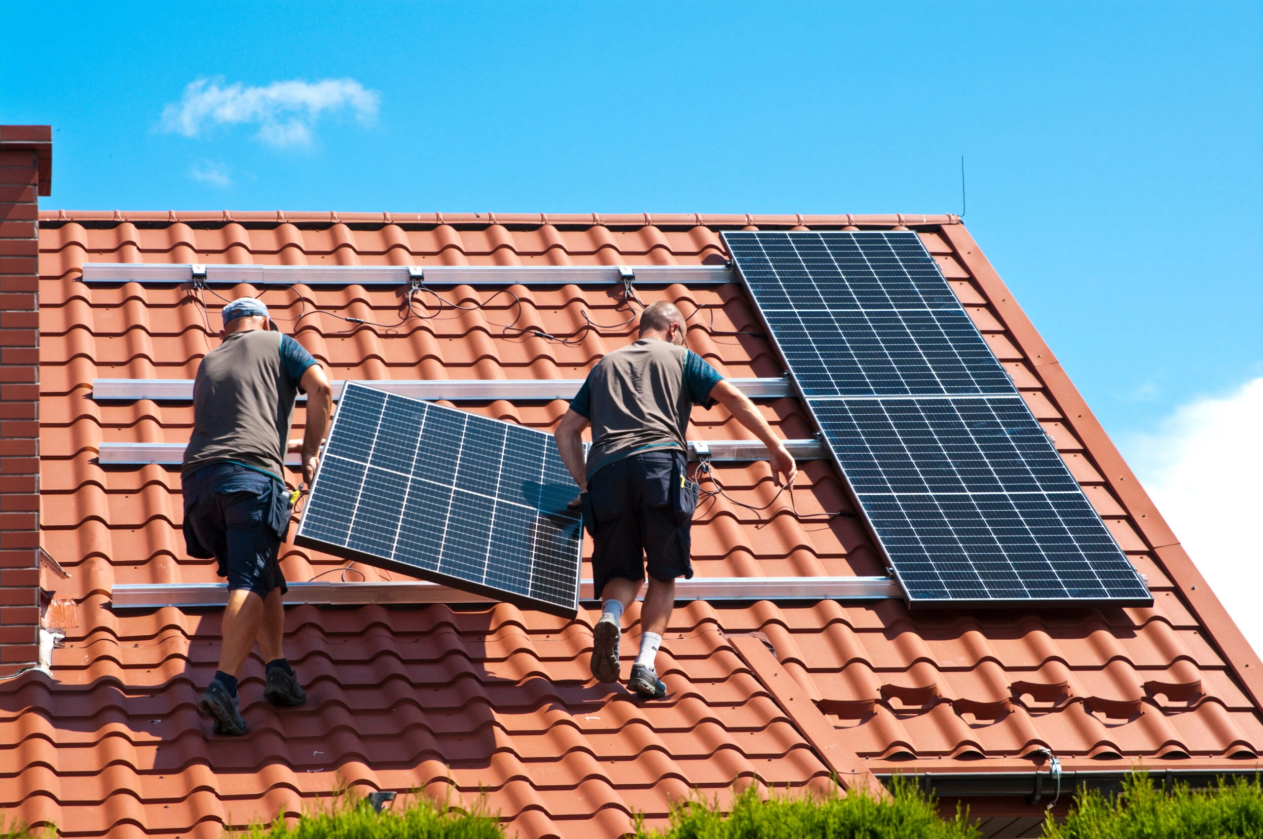 Deux techniciens posant des panneaux solaires sur un toit en tuiles