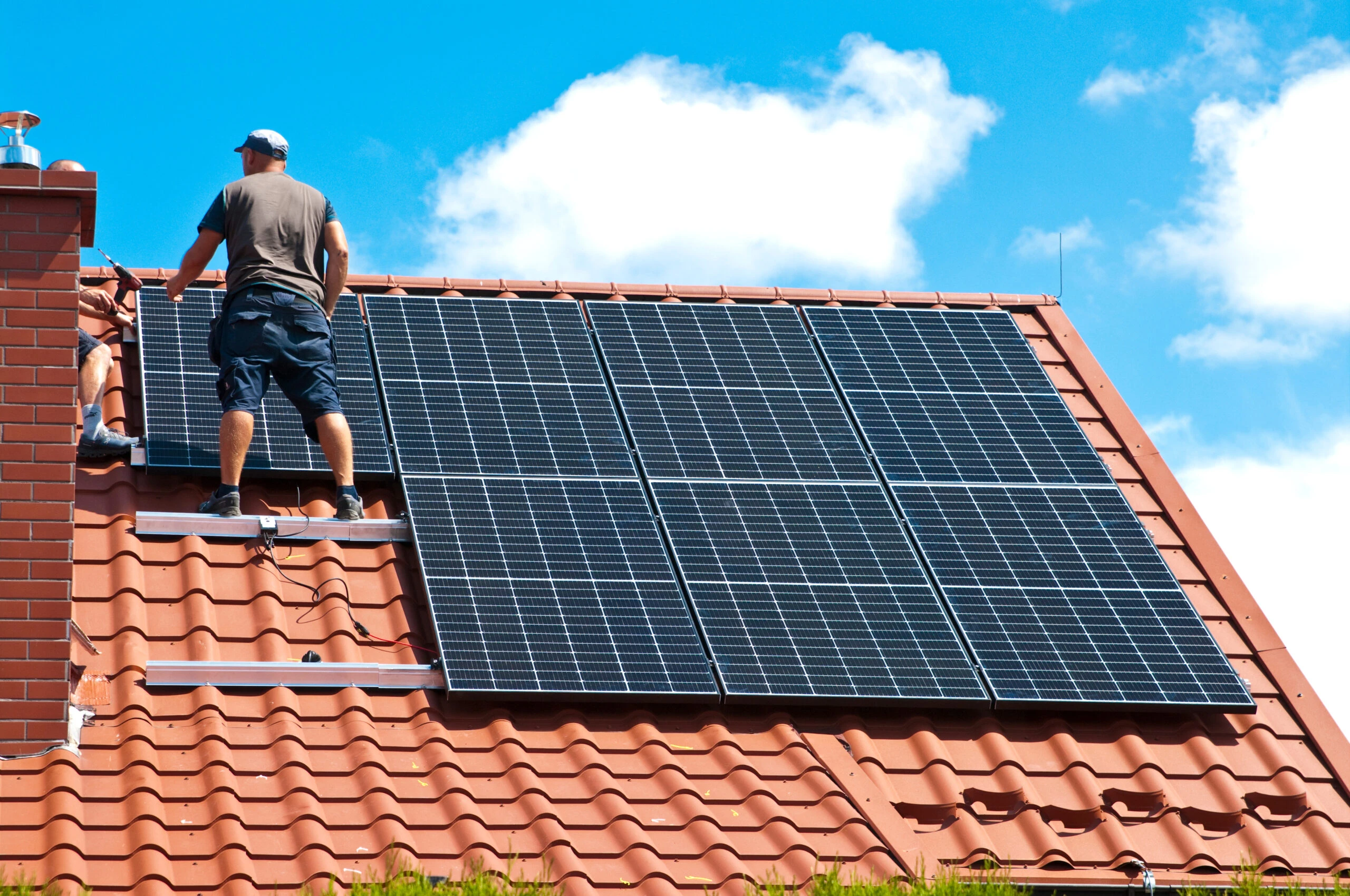 Installateur sur un toit en tuiles équipé de panneaux solaires