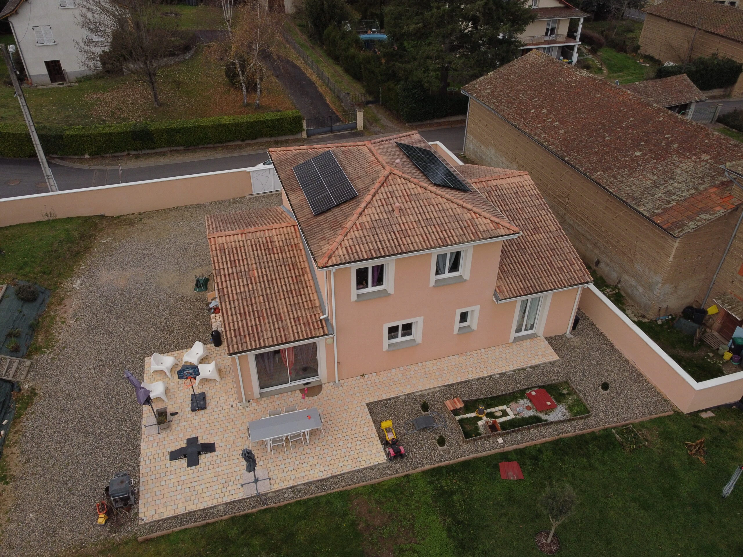 Maison crépie avec panneaux solaires et cour, vue du ciel