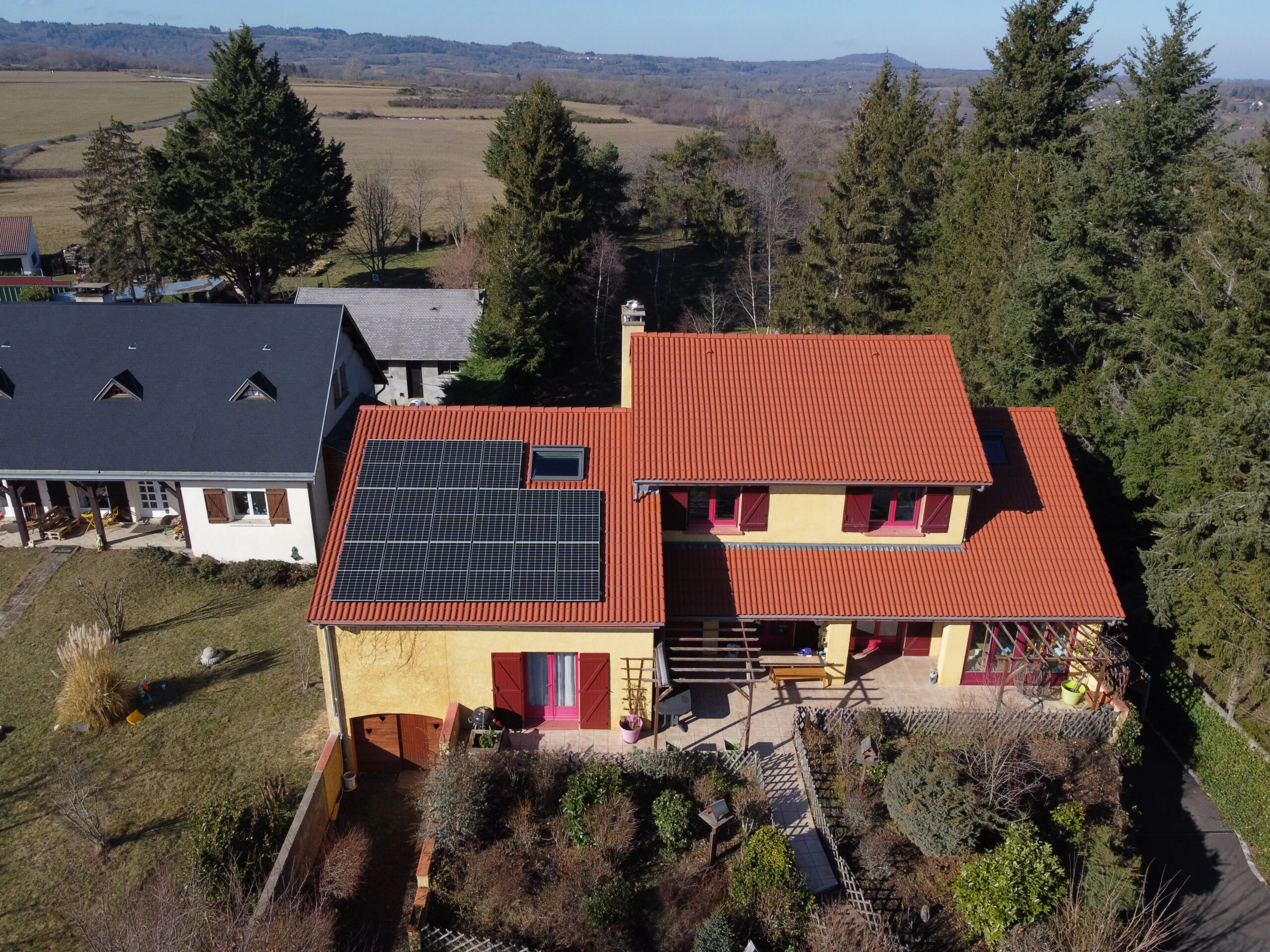Maison aux tuiles rouges équipée de panneaux solaires, vue aérienne