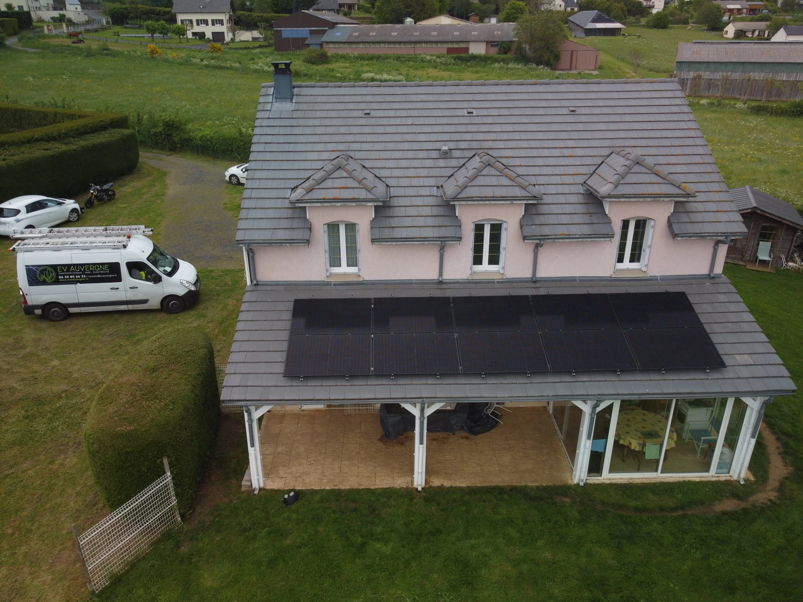 Maison à deux étages avec une rangée de panneaux solaires noirs