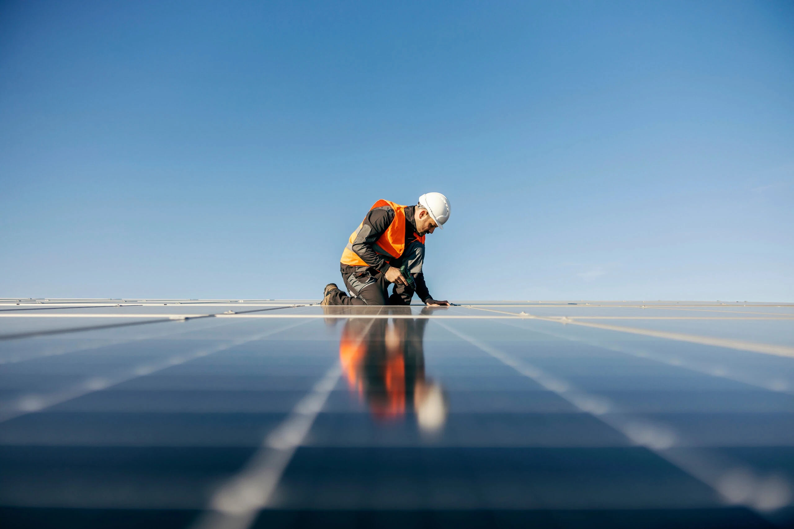 Technicien EV Auvergne agenouillé sur une grande toiture couverte de panneaux solaires