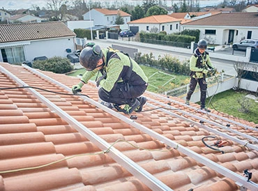 Deux techniciens fixant les rails d’une centrale solaire sur une toiture