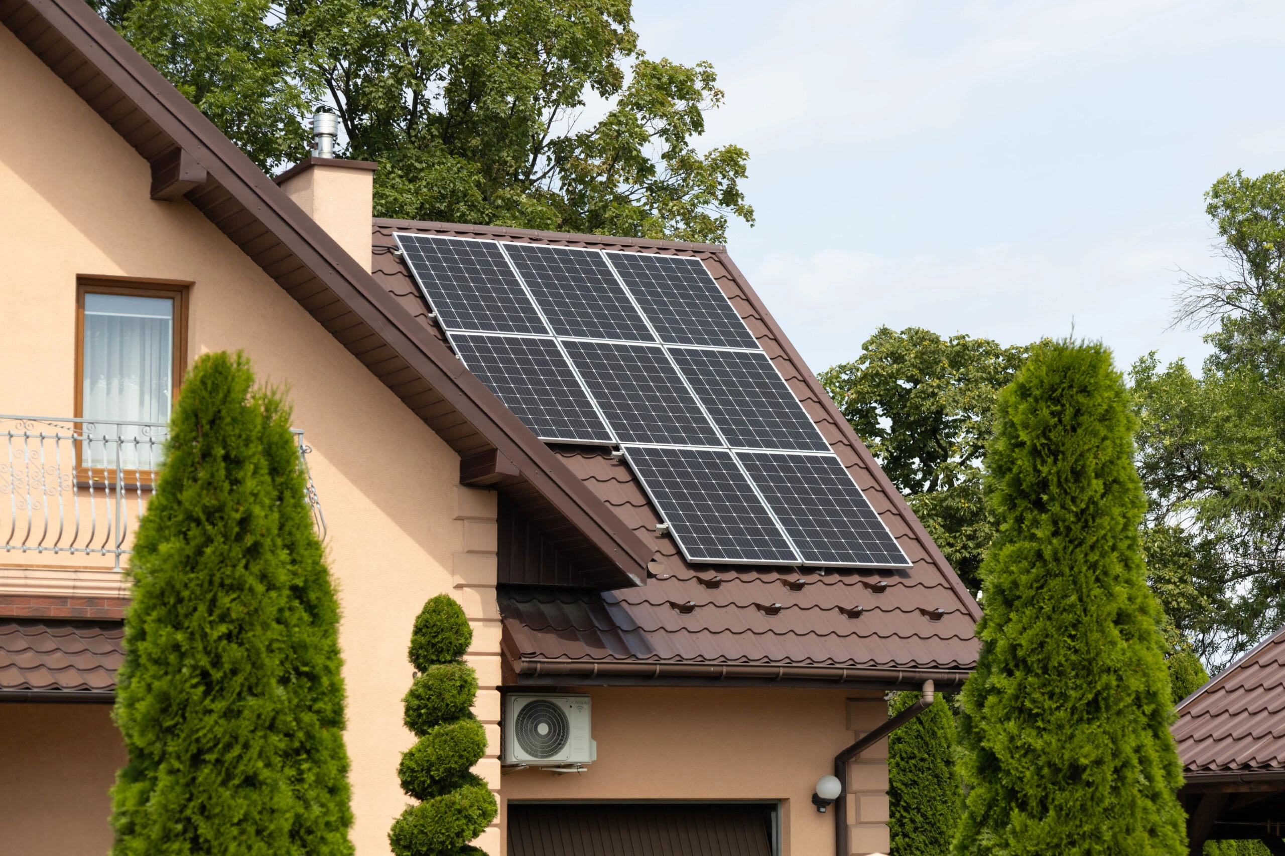 Maison équipée de panneaux solaires entourée de thuyas