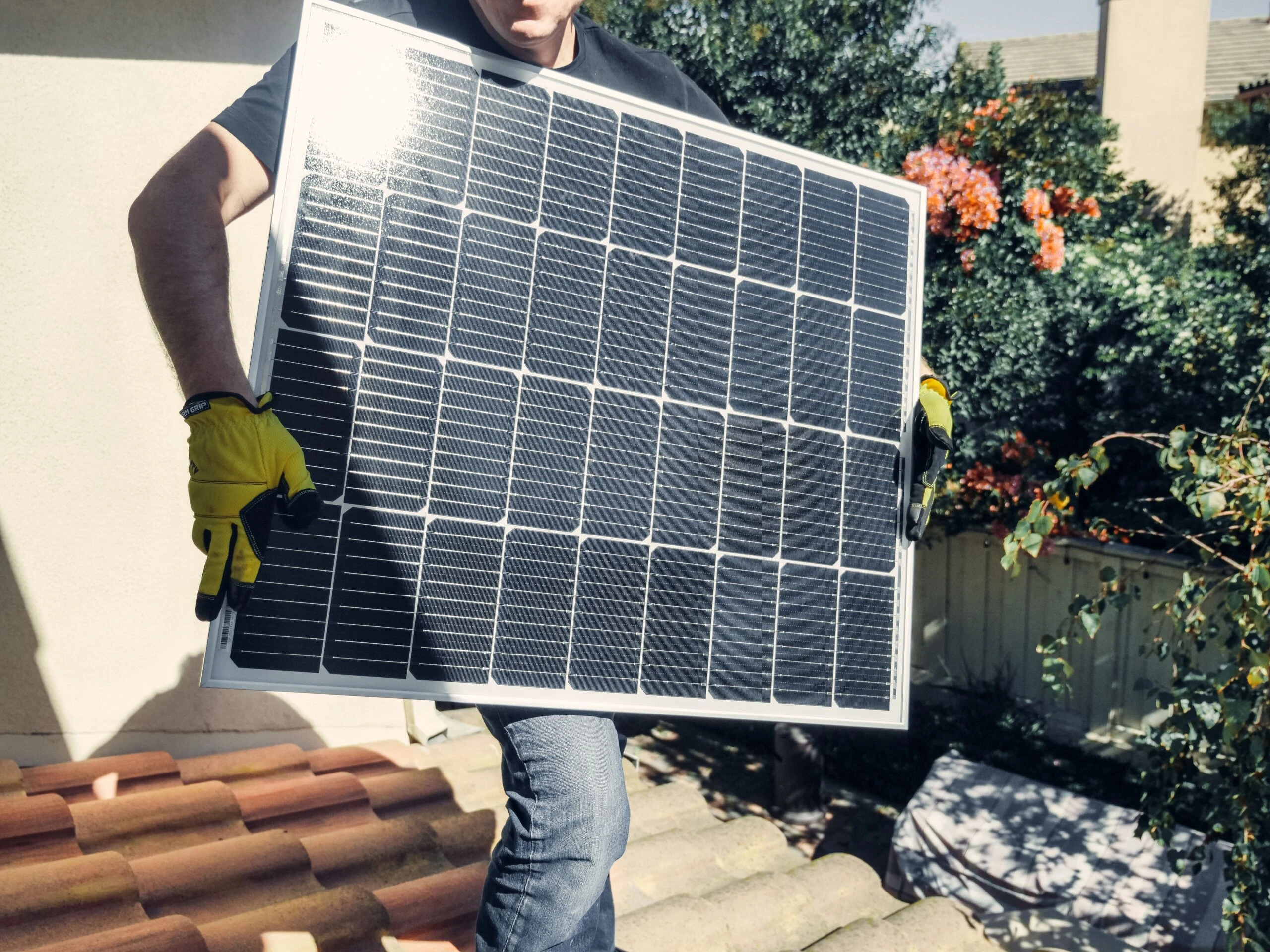 Technicien portant un panneau solaire sur un chantier